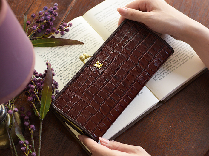 購入したアンティーククロコシリーズのスリムガマグチ長財布を両手でそっと持ち、眺めている様子。